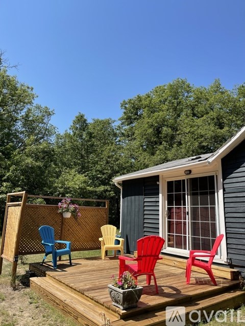 A small house with a deck and four chairs.
