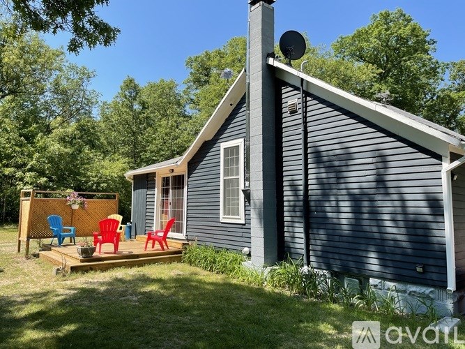 A small house with a grey siding and a brown roof with a satellite dish on top.