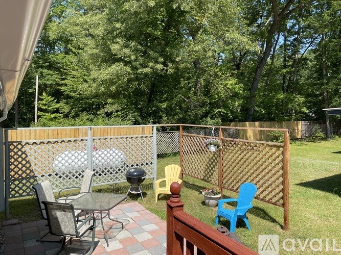 A patio with a table and chairs overlooking a fenced backyard.
