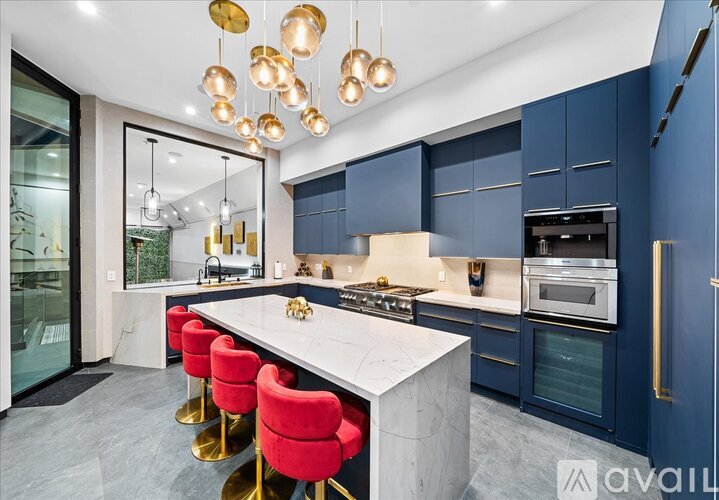 A modern kitchen with a marble countertop and red bar stools.