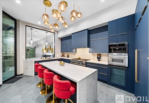A modern kitchen with a marble countertop and red bar stools.
