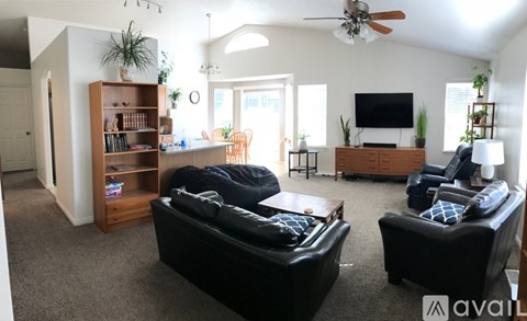 A living room with a black leather couch and a wooden bookshelf.