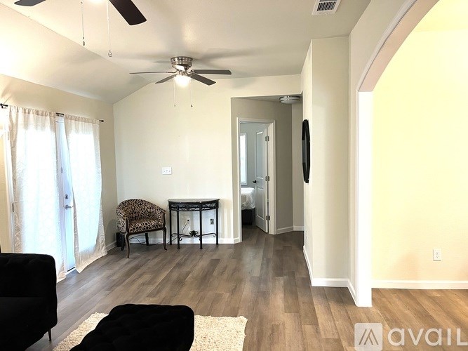 A living room with a black couch, a chair, and a ceiling fan.