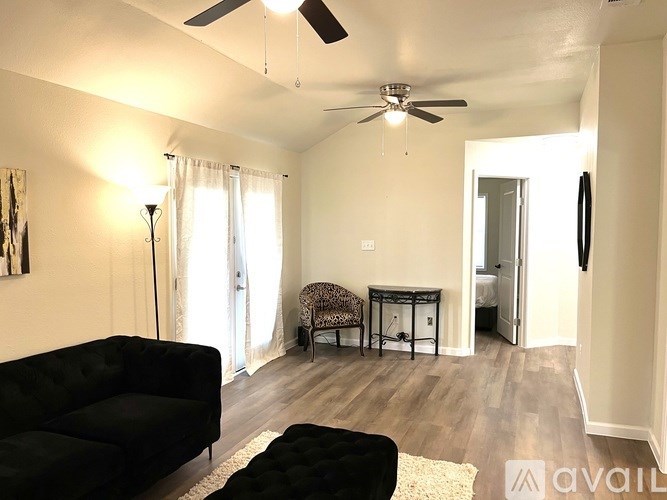A living room with a black couch and a ceiling fan.