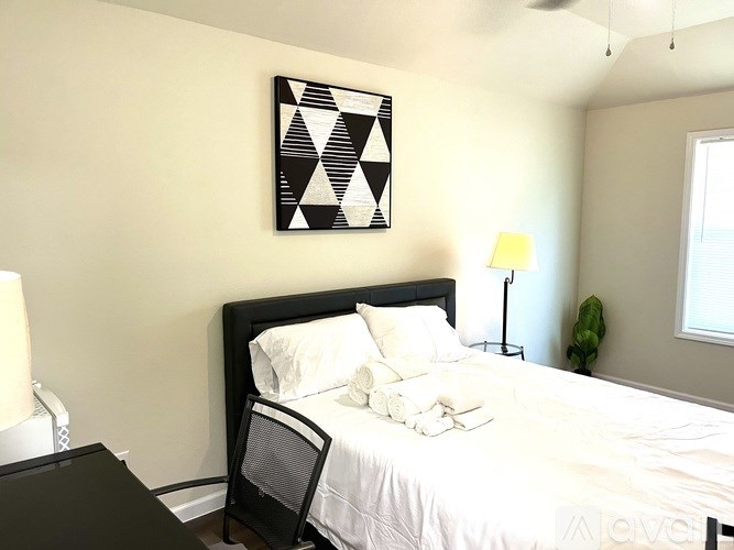 A bedroom with a bed, nightstand, lamp, and a picture on the wall.