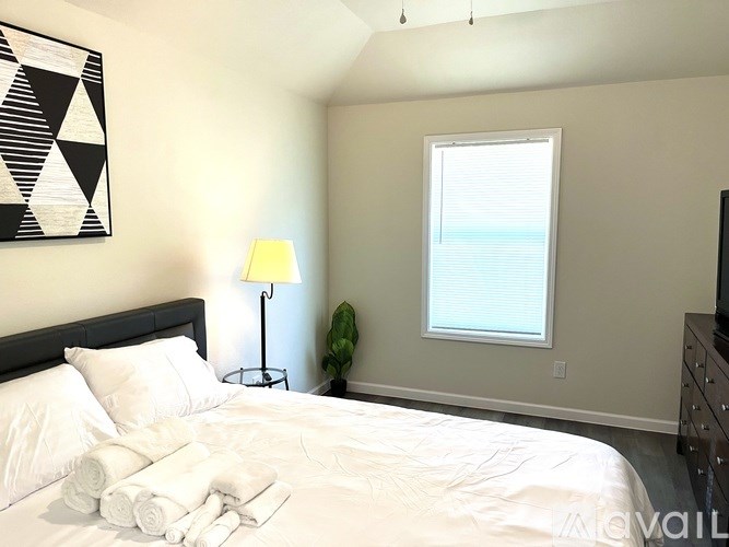 A bedroom with a bed, lamp, and a window.