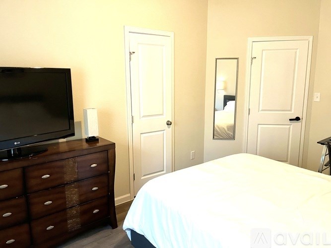 A bedroom with a bed, dresser, and television.
