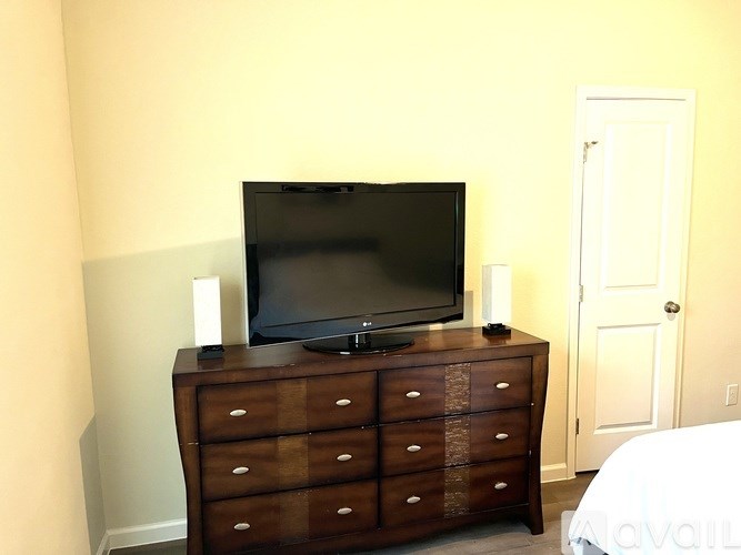 A black television on a wooden dresser in a room.