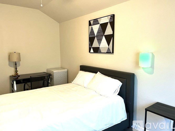 A bedroom with a bed, desk, and lamp.