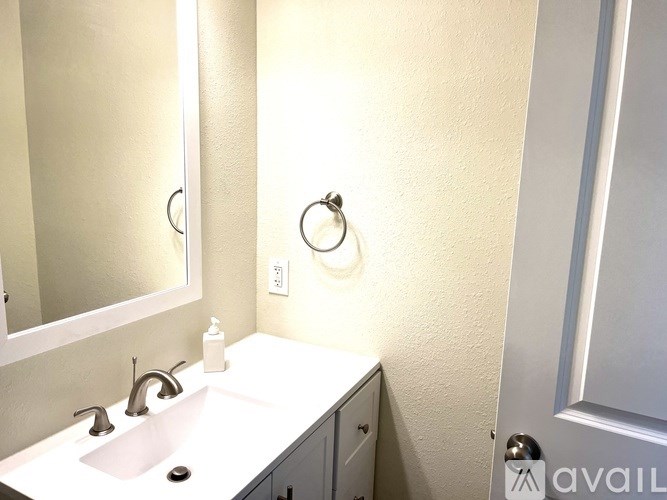 A bathroom with a sink, mirror, and a door.