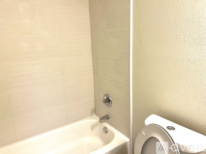 A white bathtub sits next to a white toilet in a bathroom.