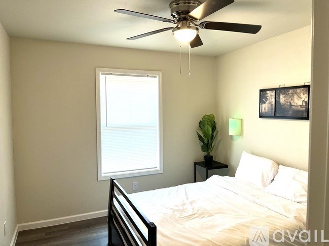 A bedroom with a bed, a ceiling fan, and a window.