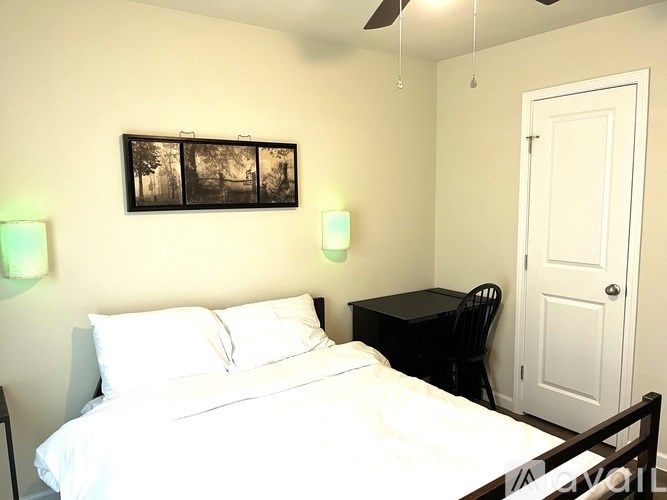 A bedroom with a bed, chair, and painting on the wall.