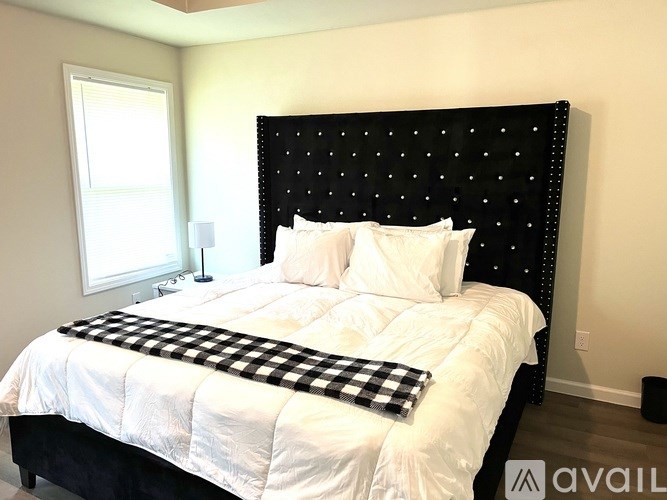 A bed with a black headboard and a checkered throw blanket.