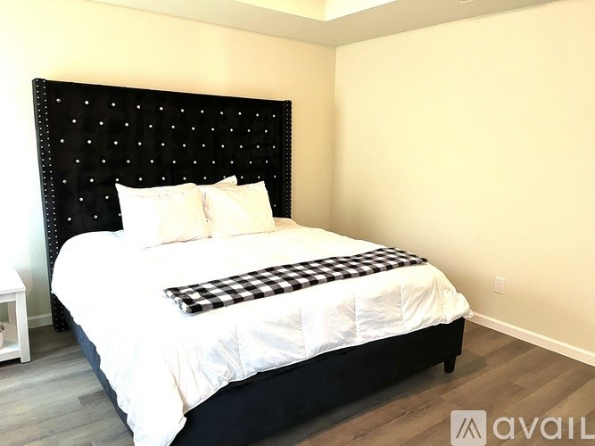A bed with a black headboard and a checkered pillowcase is in the image.