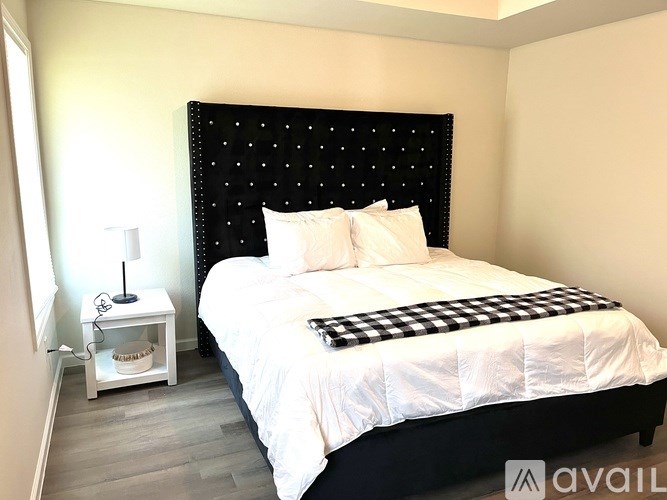 A bedroom with a black headboard and white bedding.