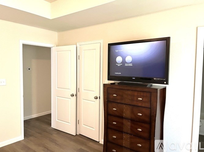 A television is on a dresser in a room with two doors.