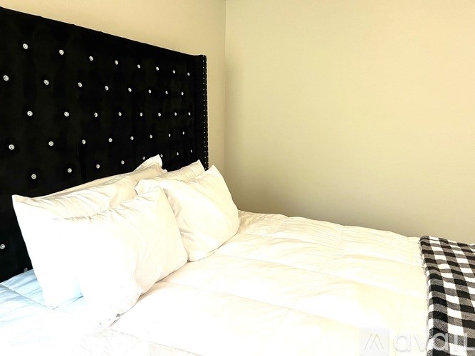 A bed with white sheets and a black headboard with white dots.