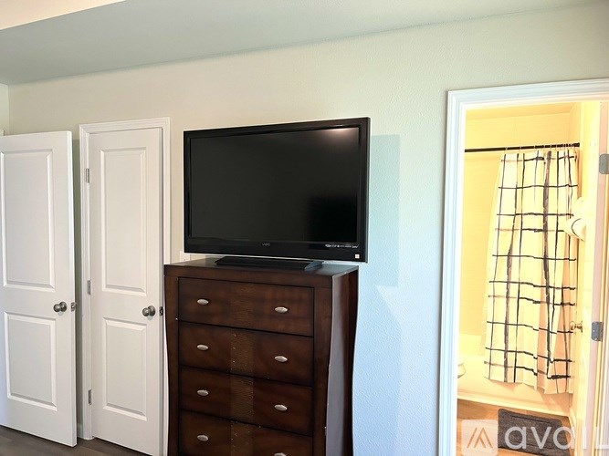 A black television sits on top of a wooden dresser in a room.