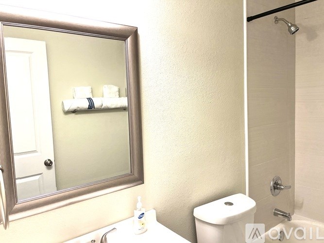 A bathroom with a toilet, sink, mirror, and towel rack.