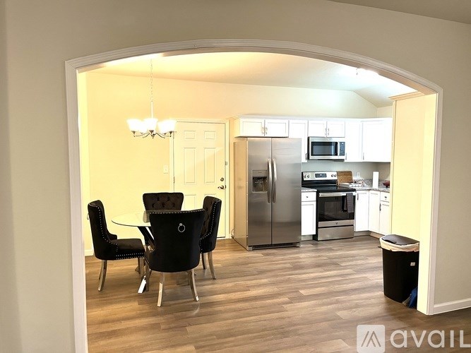 A kitchen with a table and chairs in the foreground and a refrigerator, microwave, and oven in the background.