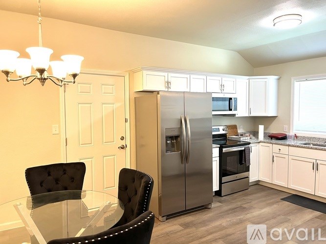 A kitchen with a table and chairs in the foreground and a refrigerator and microwave in the background.