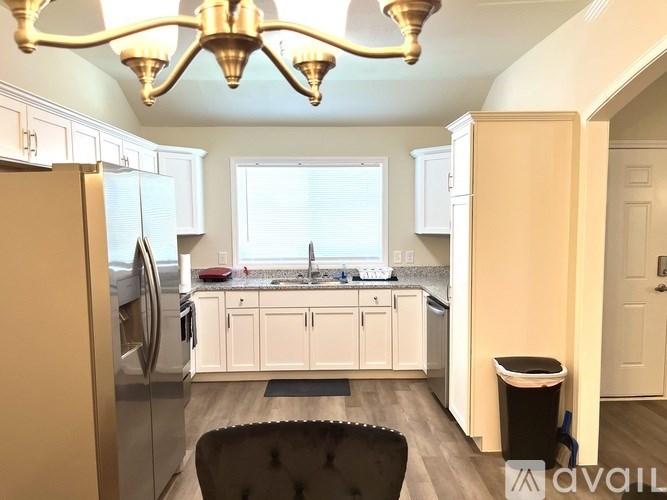A kitchen with a black chair and a fridge.
