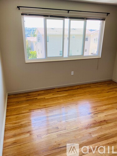 A room with wooden flooring and a window with blinds.