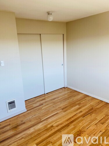 A room with wooden floors and white walls with two closets.