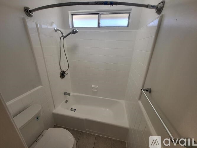 A white bathroom with a toilet, tub, and window.