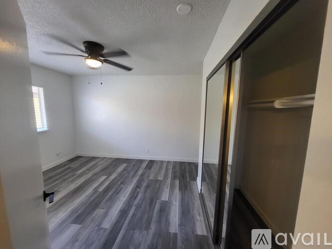 A room with a ceiling fan and wooden flooring.