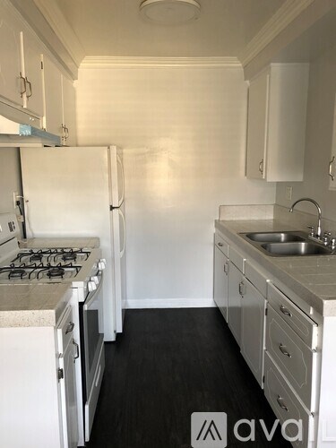 A white kitchen with a stove, sink, and cabinets.
