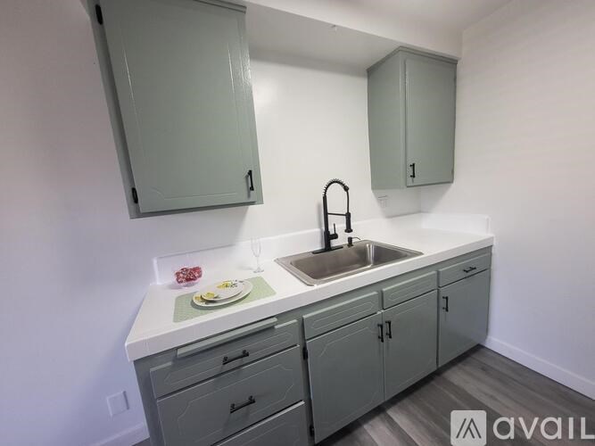 A kitchen with a sink, faucet, and cabinets.