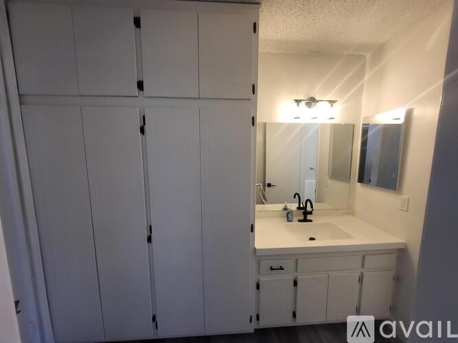 A bathroom with a white sink and cabinets.
