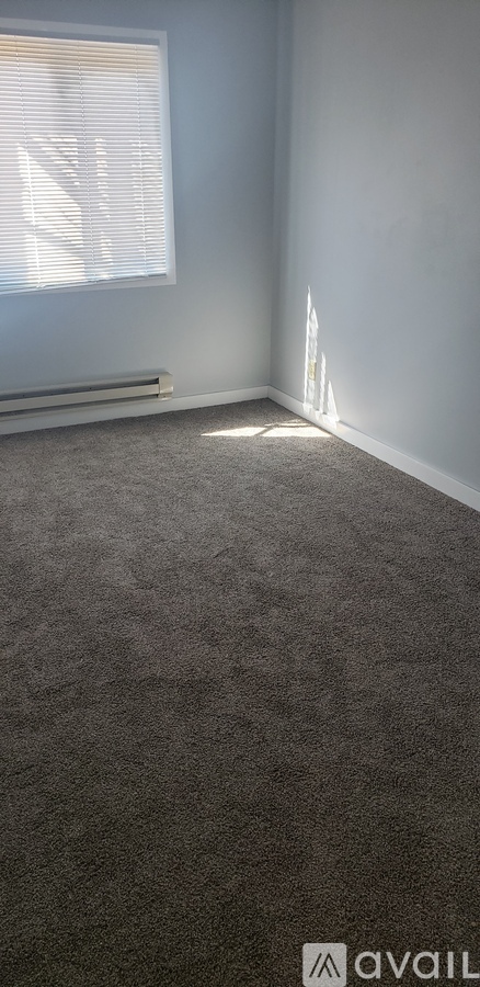 A room with a carpeted floor and a window with blinds.