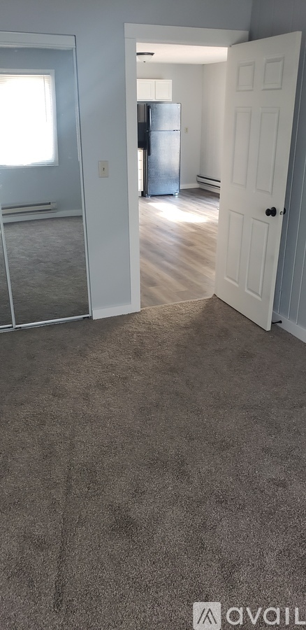A room with a carpeted floor and a door leading to another room.