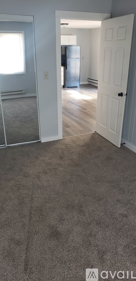 A room with a carpeted floor and a door leading to another room.