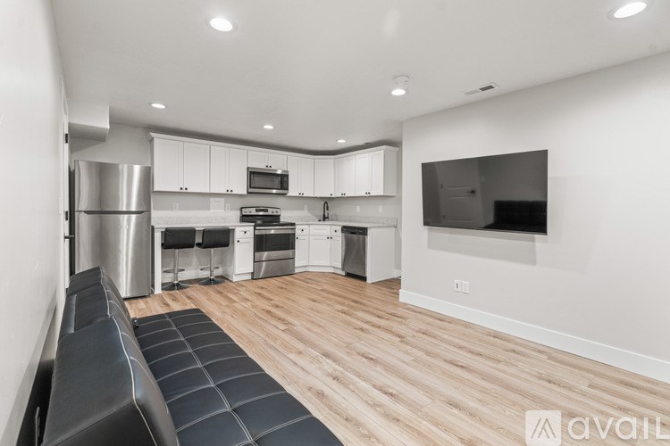 A modern kitchen with stainless steel appliances and a wooden floor.