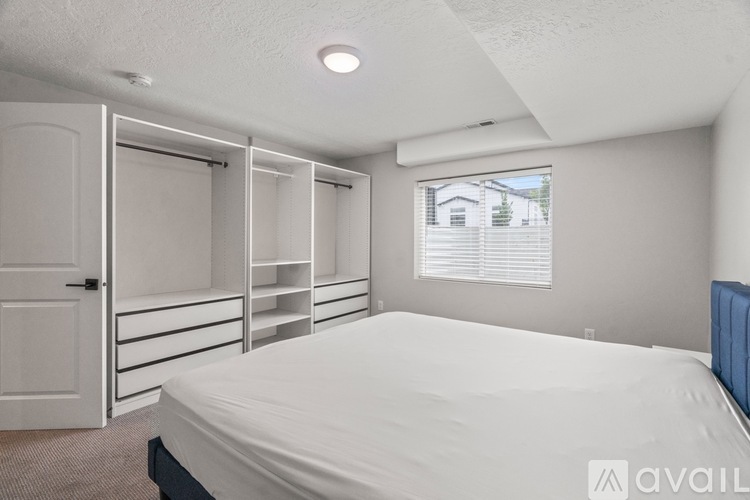 A bedroom with a bed, a window with blinds, and a closet with shelves.