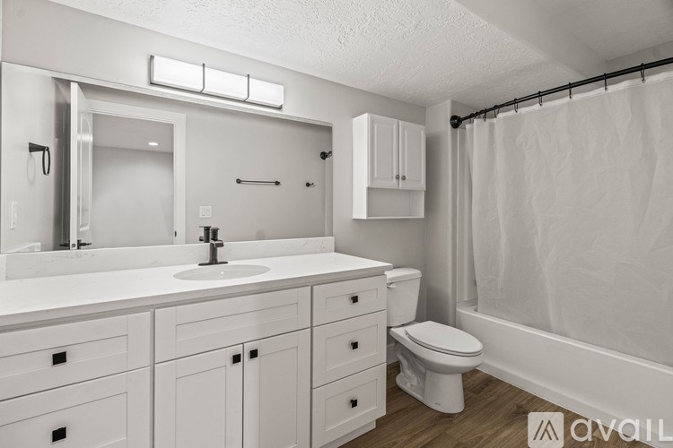 A white bathroom with a sink, toilet, and shower.