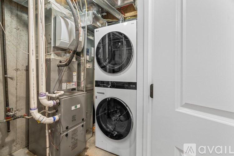 A white dryer is in a room with a lot of pipes.
