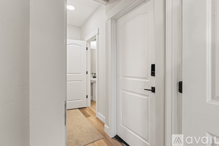 A hallway with white doors and a beige rug.