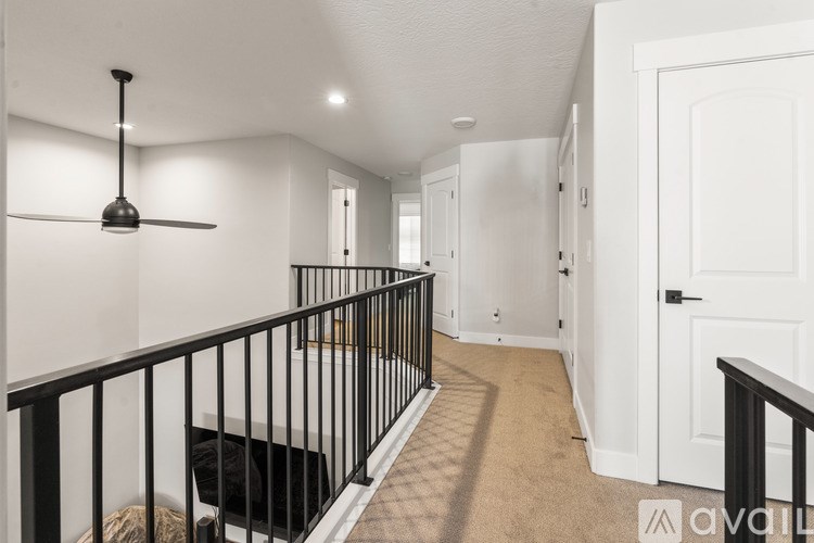 A long hallway with a black railing and a fan on the ceiling.
