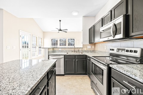 A kitchen with black cabinets and granite countertops.