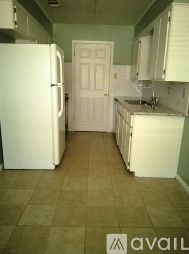 A kitchen with a white refrigerator and white cabinets.