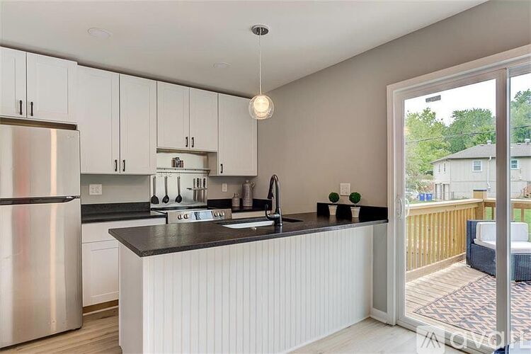 A modern kitchen with white cabinets and a black countertop.