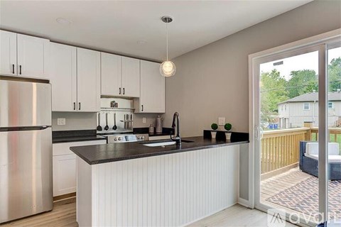 A modern kitchen with white cabinets and a black countertop.