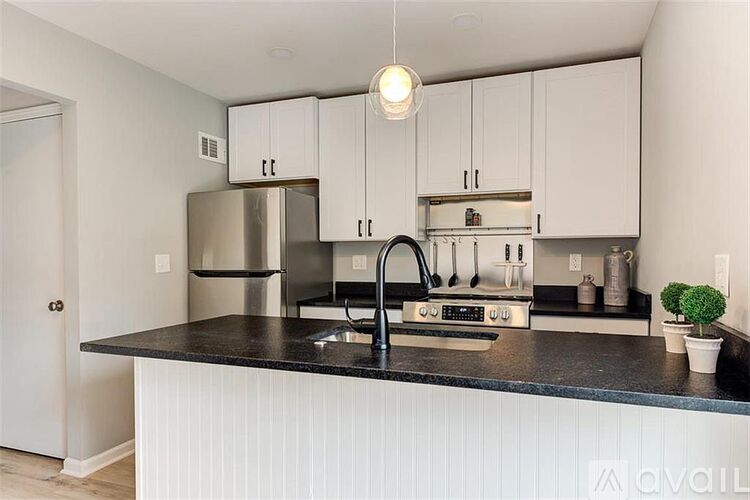 A kitchen with white cabinets and a black countertop.