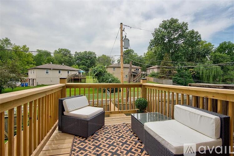 A wooden deck with two wicker chairs and a table.