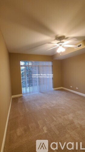 A room with a fan and a window with blinds.